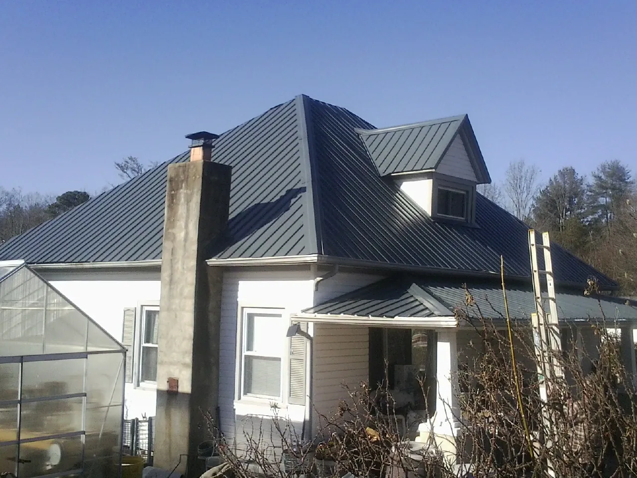 Dark blue standing seam metal roof on a white farmhouse with dormer — Slate & Tile Roof Repair by Roofing Brothers in Geuda Springs