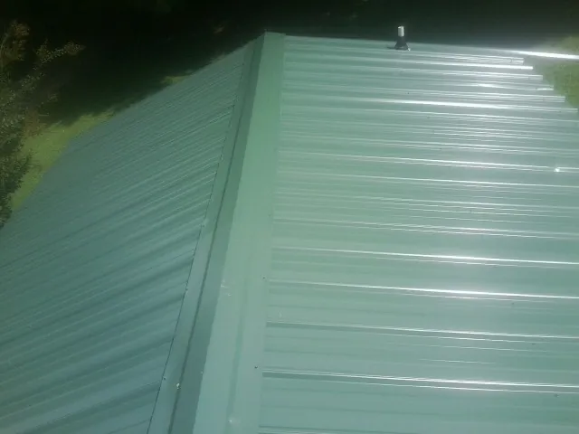 New green metal panels meeting at the ridge of a roof — Flat Roof Repair work by our crew in Geuda Springs