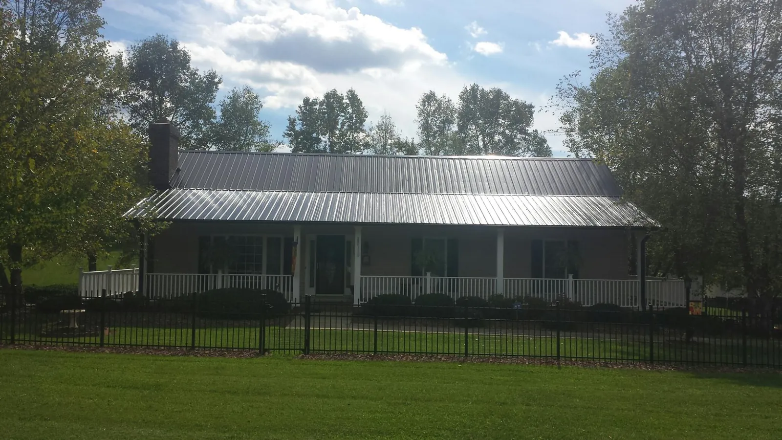 Gray metal roof on a brick ranch with a full width front porch — Gutter Guard Installation work by our crew in Geuda Springs