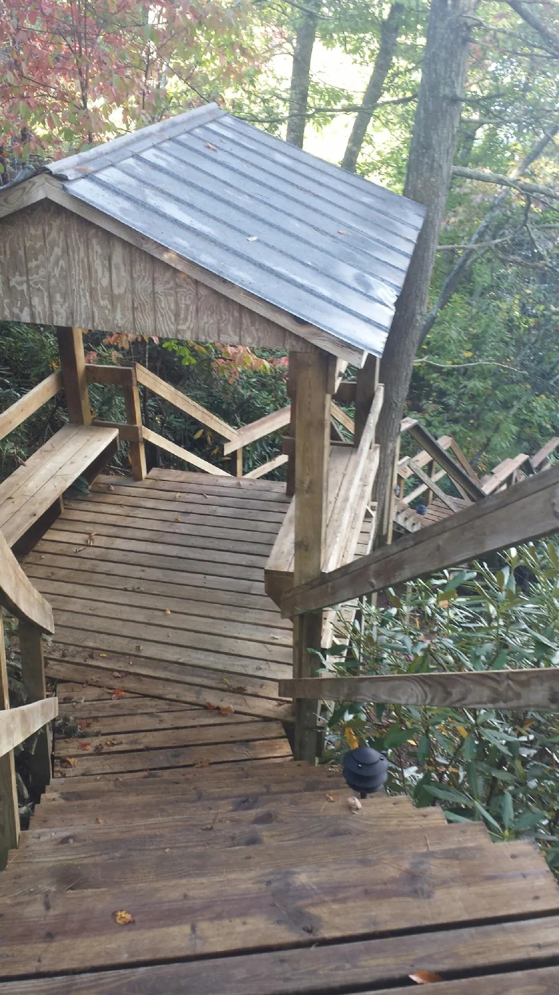 Metal roofed shelter over wooden steps on a wooded walkway — Skylight Repair & Installation work by our crew in Geuda Springs