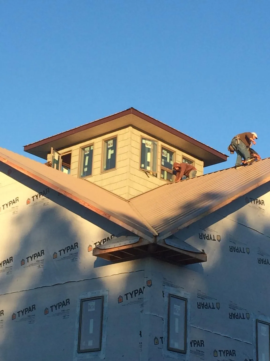 Roofers working around a rooftop cupola on a new metal roof at sunset — Roof Waterproofing in Geuda Springs by Roofing Brothers